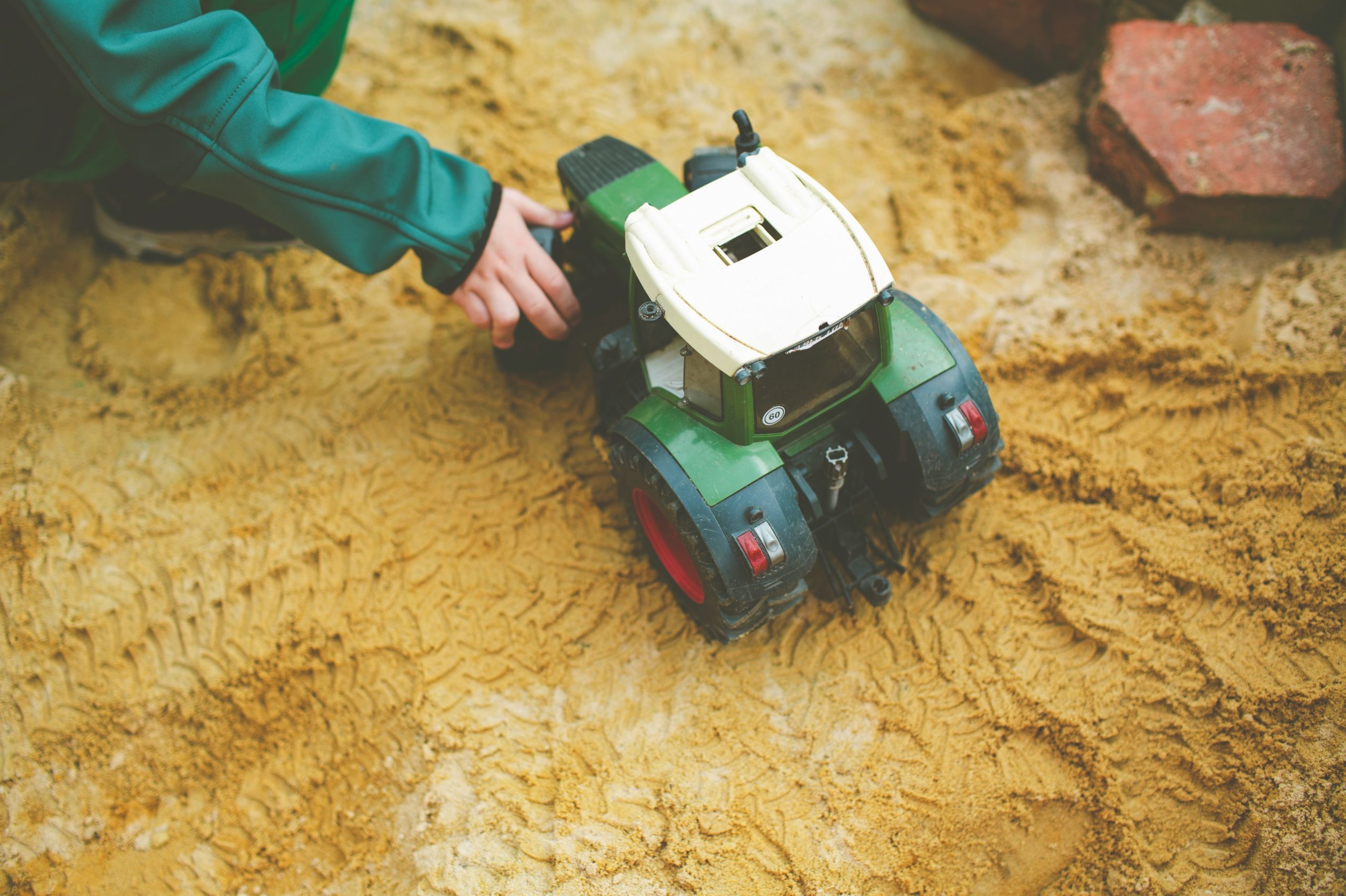 Green and white tractor on sand